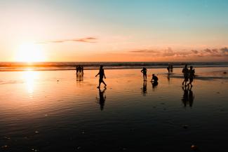 people at the beach during golden hour by George Bakos courtesy of Unsplash.